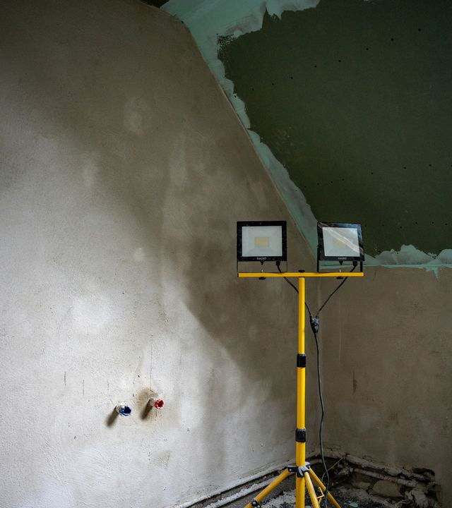 Vers gepleisterde muur met werflampen op een statief