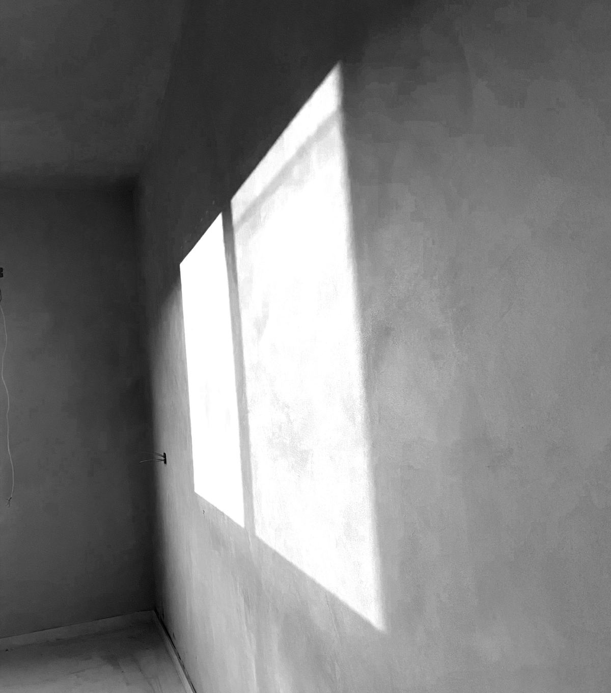 Zonlicht valt schuin op een gladde, gepleisterde muur