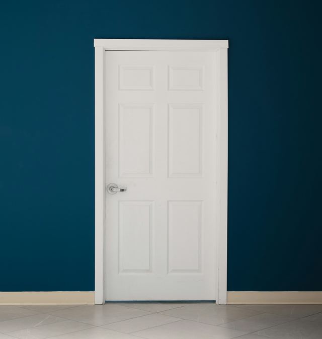 Witte paneeldeur met deurlijst in een donkerblauwe muur
